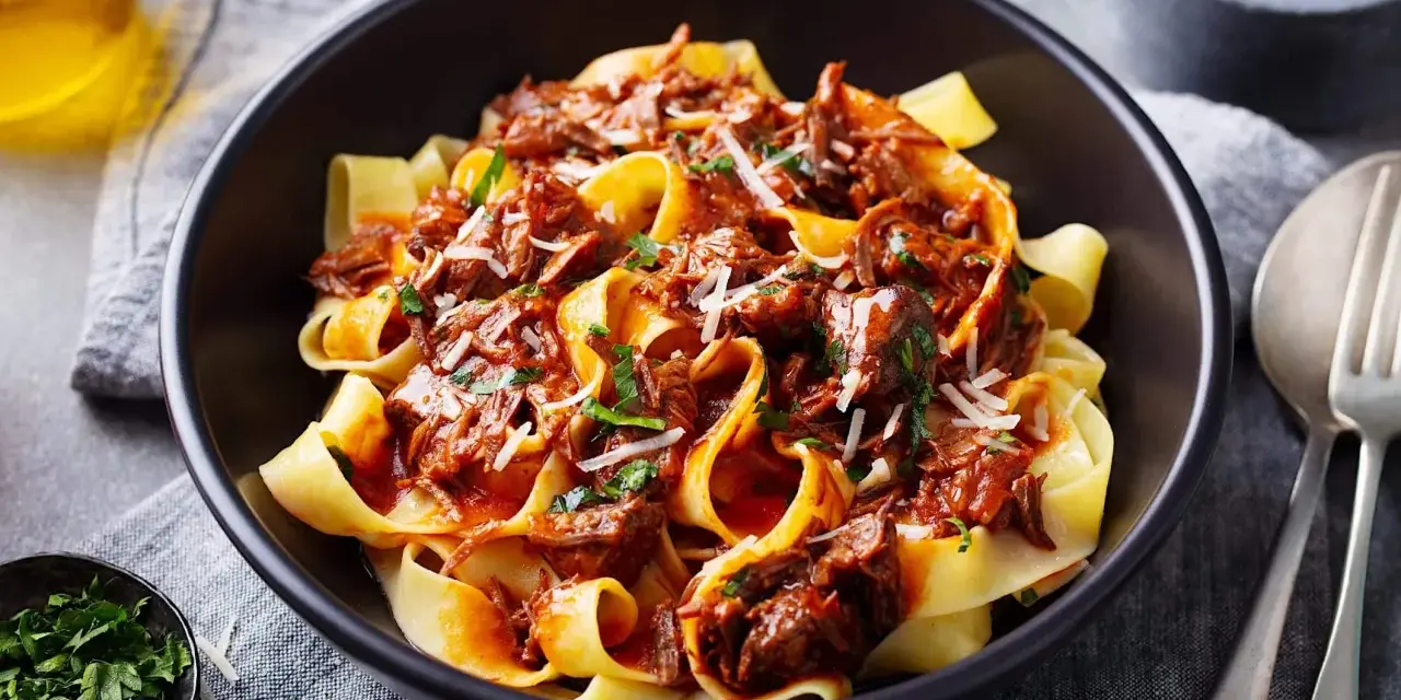 Pâtes larges nappées d'une riche sauce à la palette de boeuf effilochée, parsemées de parmesan et de persil frais.