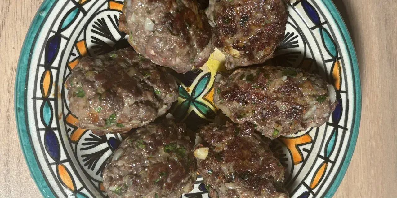 Cinq boulettes de kefta, prêtes à être dégustées, sur une assiette décorée. Une recette simple et savoureuse.