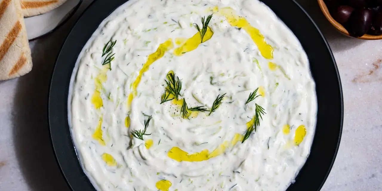 Un plat de tzatziki crémeux, garni d'aneth frais et d'huile d'olive. Parfait pour accompagner votre recette de tzatziki maison.