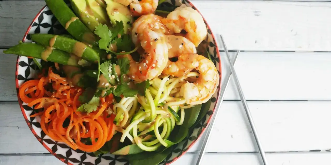 Un poke bowl crevette facile et coloré avec avocat, carottes spirales, courgettes en nouilles et pois gourmands.
