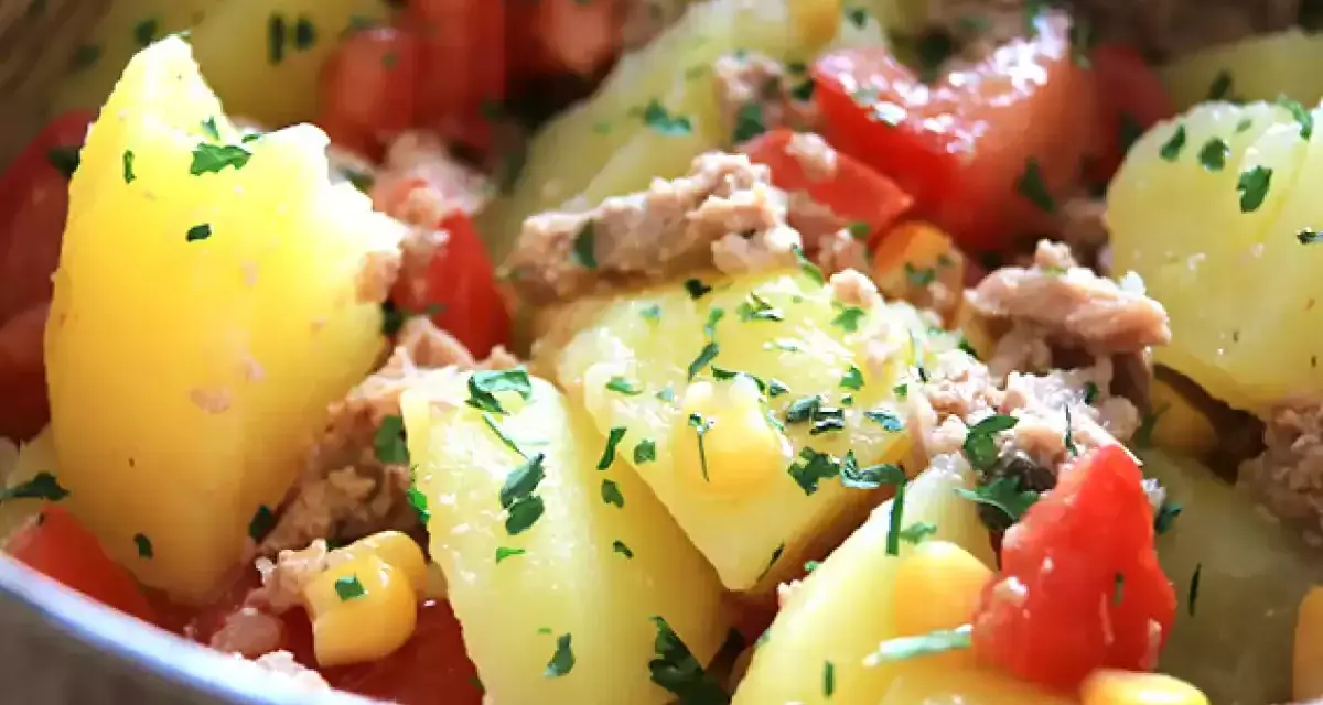 Salade de pommes de terre, thon, tomates et maïs, garnie de persil frais. Un plat simple et savoureux.