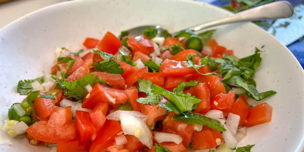 Un bol de pico de gallo frais, garni de coriandre, prêt à être dégusté.