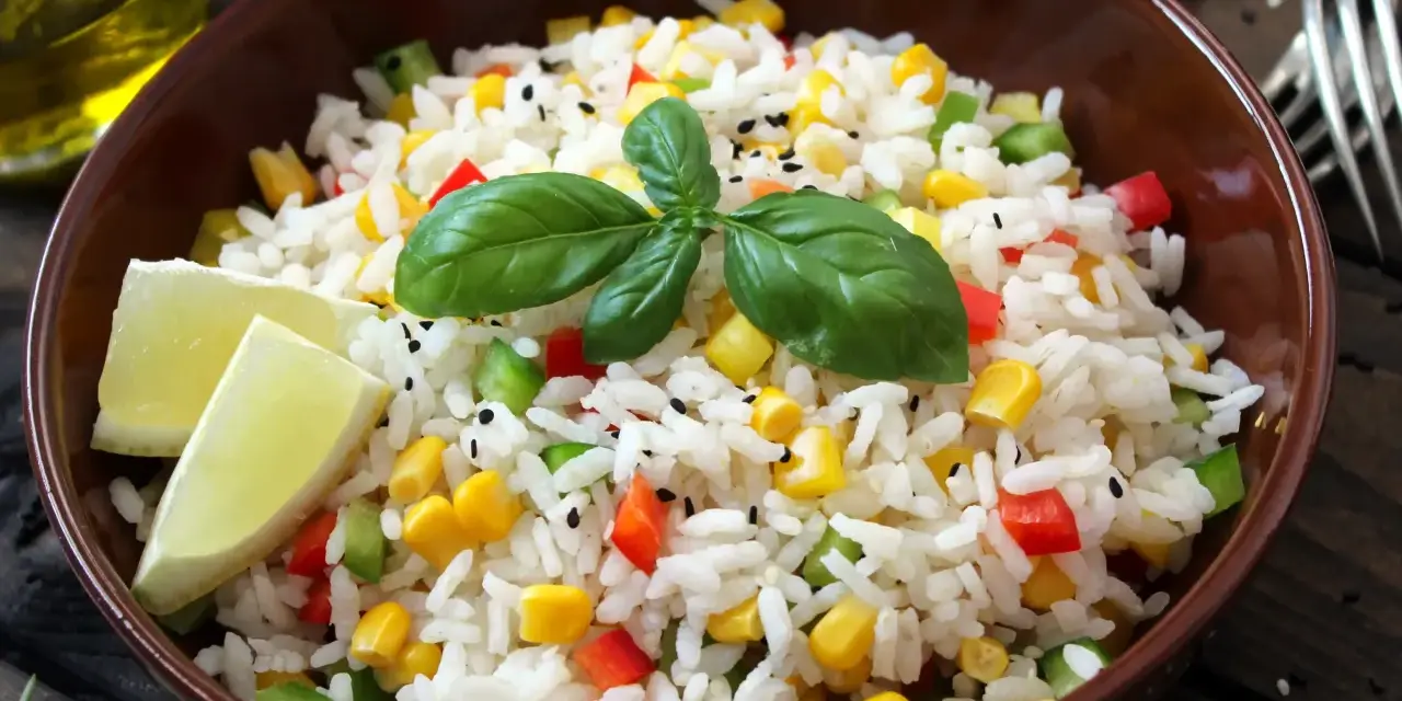 Salade niçoise riz colorée avec maïs, poivrons, basilic et quartiers de citron vert.