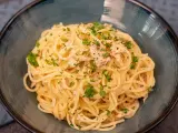 Un plat de pâtes au thon, garni de persil frais et de poivre noir, servi dans un bol bleu.