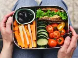 Un bento sain avec sandwich, bâtonnets de carottes et céleri, tomates cerises, concombres et olives noires.