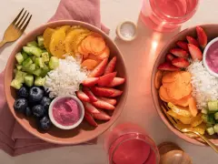 Deux bols colorés remplis de riz, fraises, myrtilles, concombre, carottes et oranges. Une belle idée poke bowl pour un repas frais et sain.