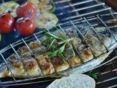 Dorade au barbecue, grillée à la perfection avec des tomates et courgettes, garnie de romarin. Un délice estival.