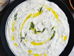 Un plat de tzatziki crémeux, garni d'aneth frais et d'huile d'olive. Parfait pour accompagner votre recette de tzatziki maison.