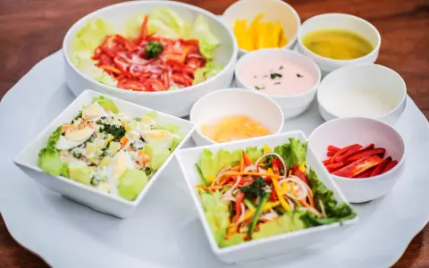 Assortiment de salades colorées avec plusieurs options de sauce pour salade, dont une rose et une verte.