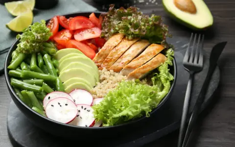 Un bol coloré avec poulet grillé, avocat, haricots verts, tomates et radis. Une idée de recette souper saine et équilibrée.