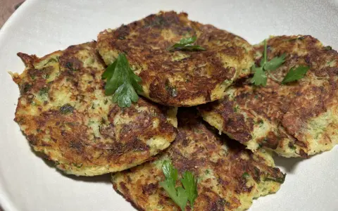 Galettes dorées de courgette et pomme de terre, garnies de persil frais, prêtes à être dégustées.