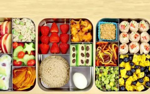 Une recette bento colorée et équilibrée : riz, fraises, crudités, sandwich, rouleaux de printemps, fruits et légumes variés.