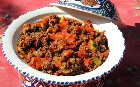 Un plat savoureux de recette viande hachée avec des légumes, servi dans un plat à tajine décoré.