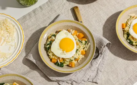 Risotto crémeux aux courges et épinards, garni d'un œuf au plat. Une recette avec des œufs qui promet un repas réconfortant.