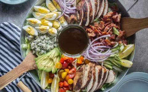 Salade généreuse avec poulet grillé, bacon croustillant, œufs durs, avocat, tomates cerises, oignons rouges et fromage bleu. Une salade kobe parfaite pour un repas complet.