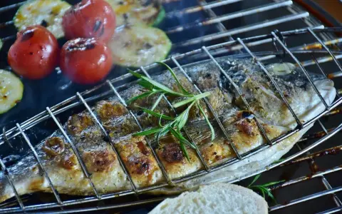 Dorade au barbecue, grillée à la perfection avec des tomates et courgettes, garnie de romarin. Un délice estival.
