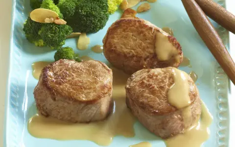 Trois médaillons de porc tendres nappés d'une onctueuse sauce moutarde, accompagnés de brocolis croquants. Un délice pour les amateurs de viande de porc.