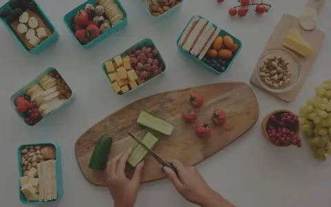 Préparation d'un panier repas travail de nuit : fruits, légumes, sandwichs, œufs, fromage et noix.