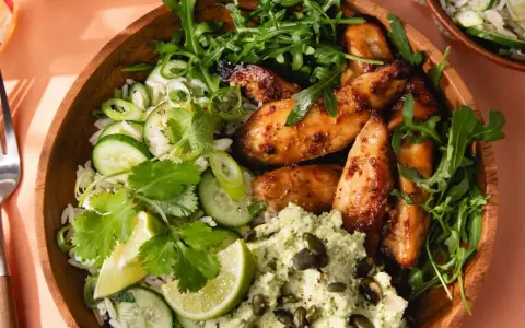 Un bol de riz avec poulet laqué, concombre, coriandre et une purée verte. Une délicieuse recette asiatique healthy.
