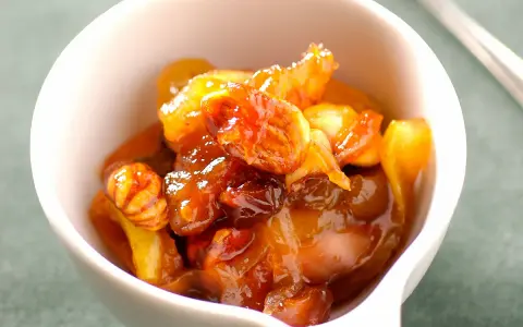 Chutney de prunes, un délice sucré-salé aux fruits confits et noix, servi dans un bol blanc.