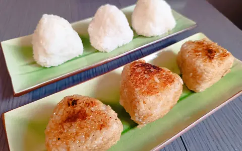 Sur des assiettes vertes, des onigiris nature et grillés, parfaits pour un pique-nique japonais.