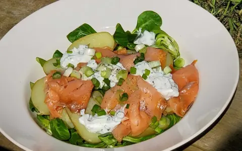 Salade nordique appétissante : saumon fumé, pommes de terre, salade verte et sauce crémeuse aux herbes. Parfait pour un repas léger.