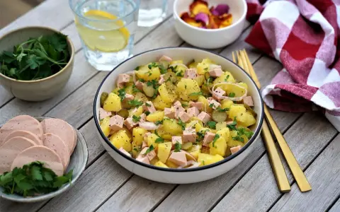 Salade strasbourgeoise appétissante avec pommes de terre, saucisse en dés, cornichons et persil frais. Un délice alsacien !