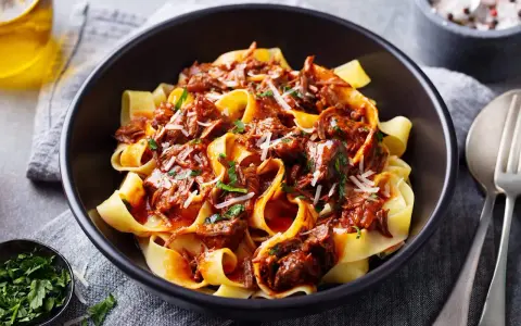 Pâtes larges nappées d'une riche sauce à la palette de boeuf effilochée, parsemées de parmesan et de persil frais.