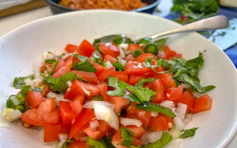 Un bol de pico de gallo frais, garni de coriandre, prêt à être dégusté.