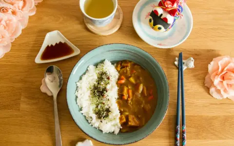 Un délicieux curry japonais avec du riz blanc, servi avec une tasse de thé et des décorations mignonnes.