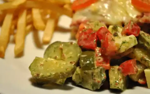 Une délicieuse salade de cornichon avec des tomates et des herbes, accompagnée de frites croustillantes.