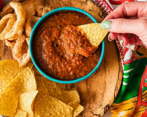 Une main trempe une chips dans une sauce salsa maison. Parfait pour une sauce salsa recette rapide et savoureuse.