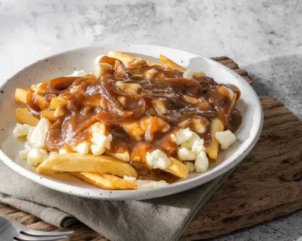 Une assiette de poutine fumante, parfaite pour une recette poutine maison facile. Des frites croustillantes, du fromage en grains et une sauce brune onctueuse.