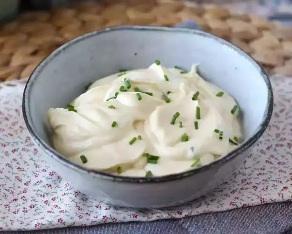 Mayonnaise sans huile crémeuse, garnie de ciboulette fraîche, dans un bol en céramique. Parfait pour un repas léger.