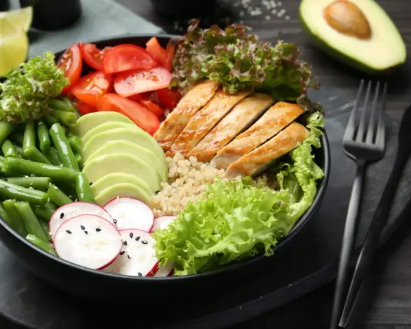 Un bol coloré avec poulet grillé, avocat, haricots verts, tomates et radis. Une idée de recette souper saine et équilibrée.