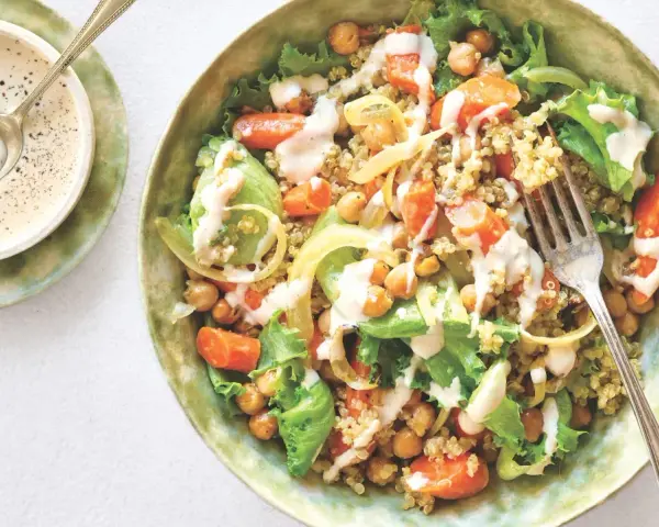 Salade colorée de quinoa, pois chiches, carottes et laitue, arrosée d'une sauce crémeuse. Une recette healthy simple et savoureuse.