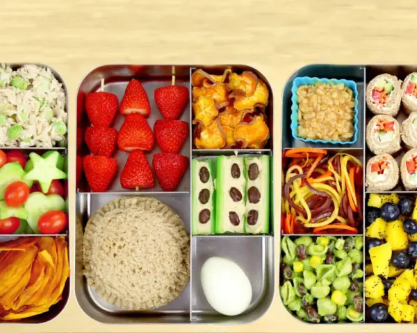 Une recette bento colorée et équilibrée : riz, fraises, crudités, sandwich, rouleaux de printemps, fruits et légumes variés.