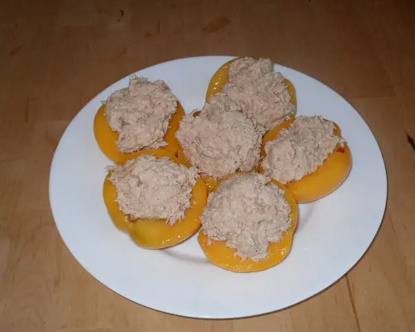 Moitié de pêches garnies d'une préparation de thon, prêtes pour un apéritif original. Une recette de pêche au thon revisitée.