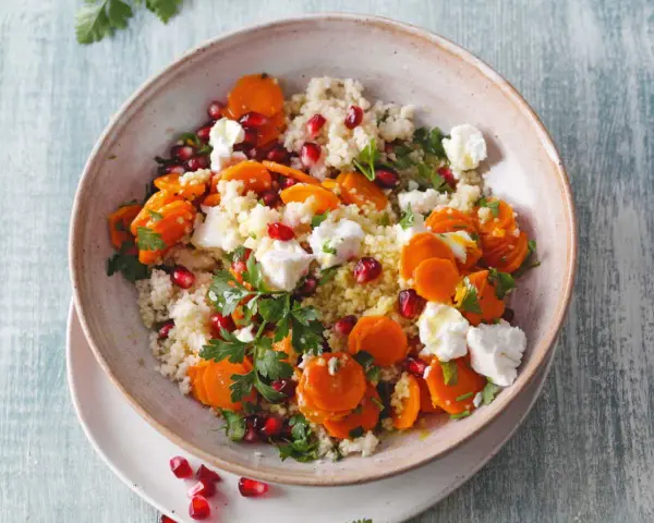 Salade de semoule colorée avec carottes, grenade et morceaux de feta. Un délice frais et savoureux.
