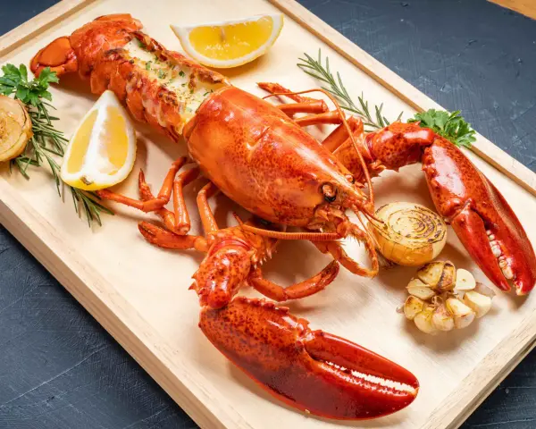 Homard entier, prêt pour la cuisson, garni de citron, d'oignons grillés et d'ail. Un délice pour les amateurs de fruits de mer.
