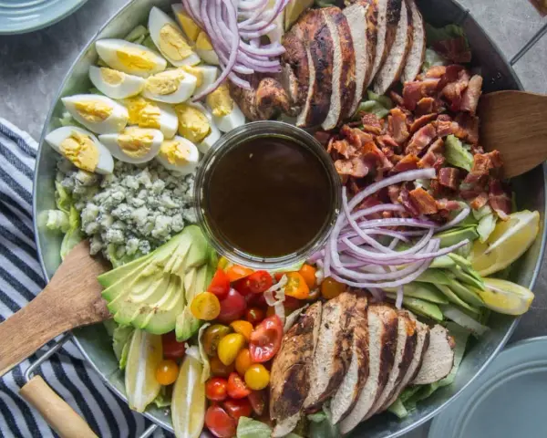 Salade généreuse avec poulet grillé, bacon croustillant, œufs durs, avocat, tomates cerises, oignons rouges et fromage bleu. Une salade kobe parfaite pour un repas complet.