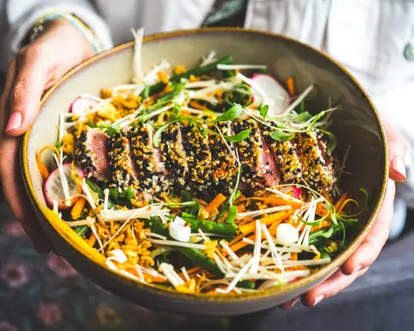 Un délicieux tataki de thon, enrobé de sésame, servi avec un accompagnement coloré de légumes croquants et de pousses fraîches.