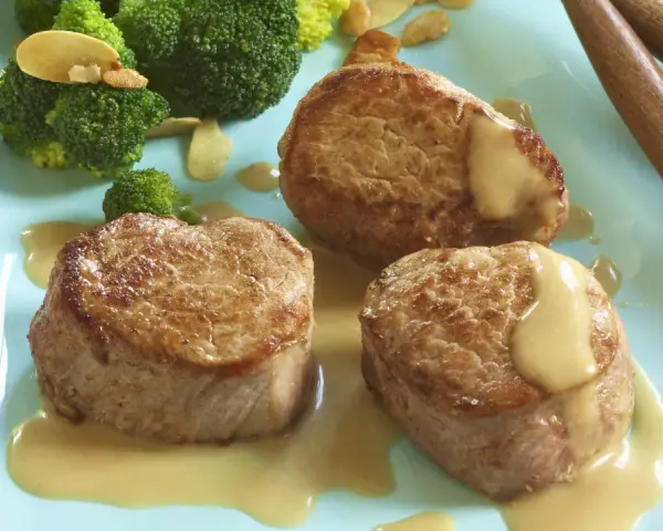 Trois médaillons de porc tendres nappés d'une onctueuse sauce moutarde, accompagnés de brocolis croquants. Un délice pour les amateurs de viande de porc.