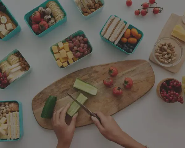 Préparation d'un panier repas travail de nuit : fruits, légumes, sandwichs, œufs, fromage et noix.