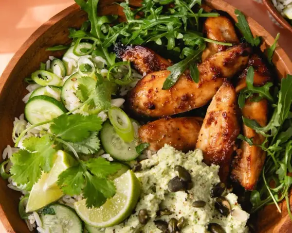 Un bol de riz avec poulet laqué, concombre, coriandre et une purée verte. Une délicieuse recette asiatique healthy.