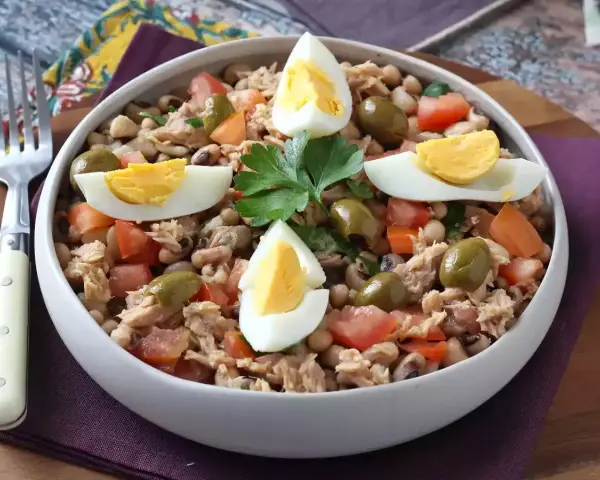 Salade de thon, haricots, tomates et olives, garnie d'œufs durs. Une idée repas facile et rapide.