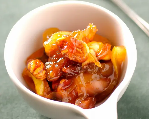 Chutney de prunes, un délice sucré-salé aux fruits confits et noix, servi dans un bol blanc.