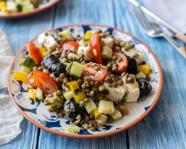Salade de lentilles colorée avec tomates, concombre, poivrons, olives noires et feta. Un plat frais et savoureux.
