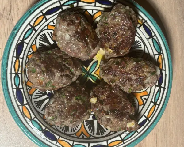 Cinq boulettes de kefta, prêtes à être dégustées, sur une assiette décorée. Une recette simple et savoureuse.