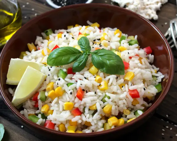 Salade niçoise riz colorée avec maïs, poivrons, basilic et quartiers de citron vert.